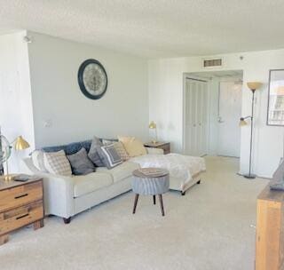 living room with visible vents, light carpet, and a textured ceiling