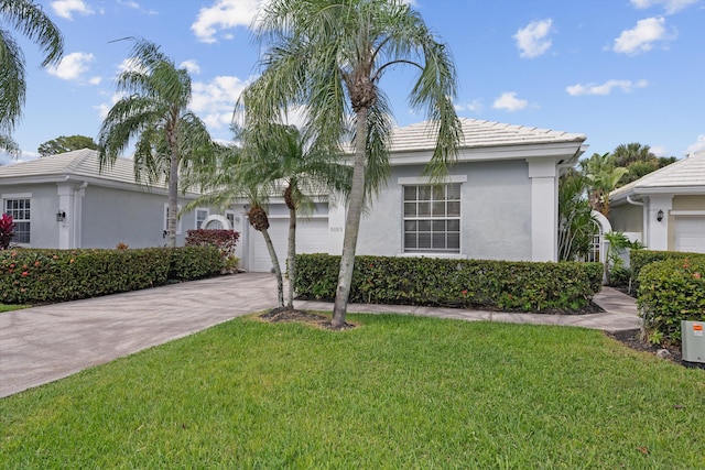 ranch-style house with an attached garage, driveway, a tiled roof, stucco siding, and a front yard