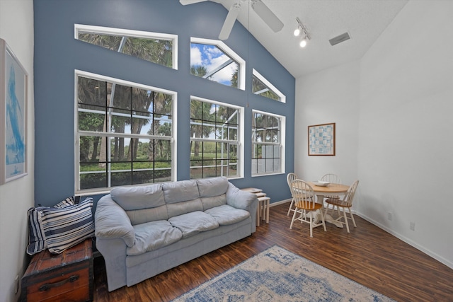 living area featuring high vaulted ceiling, visible vents, baseboards, and wood finished floors