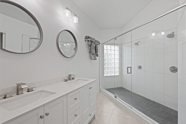 bathroom with a textured ceiling, a stall shower, tile patterned flooring, and a sink