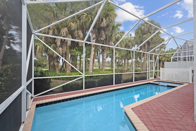 outdoor pool with glass enclosure and a patio