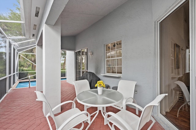 view of patio with outdoor dining area, glass enclosure, and an outdoor pool