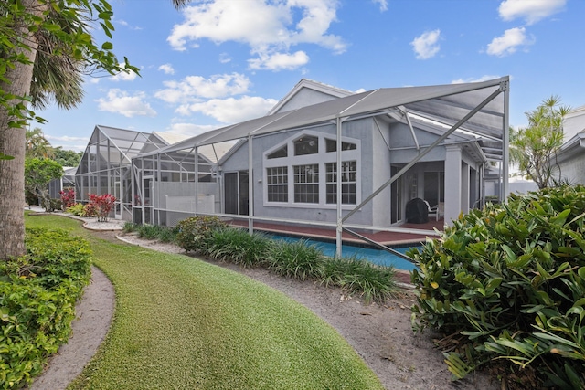 back of house featuring glass enclosure, a lawn, and an outdoor pool