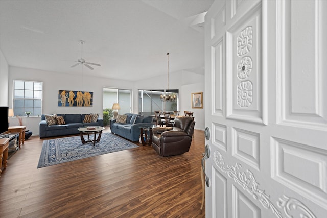 living area featuring vaulted ceiling, ceiling fan with notable chandelier, and wood finished floors