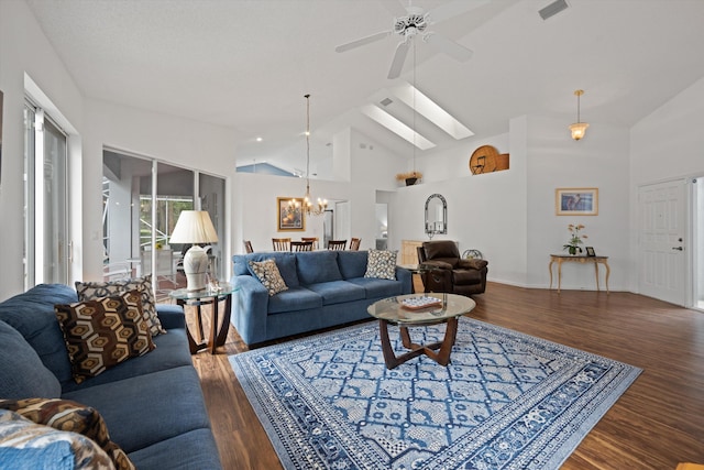 living room featuring high vaulted ceiling, ceiling fan with notable chandelier, a skylight, wood finished floors, and visible vents