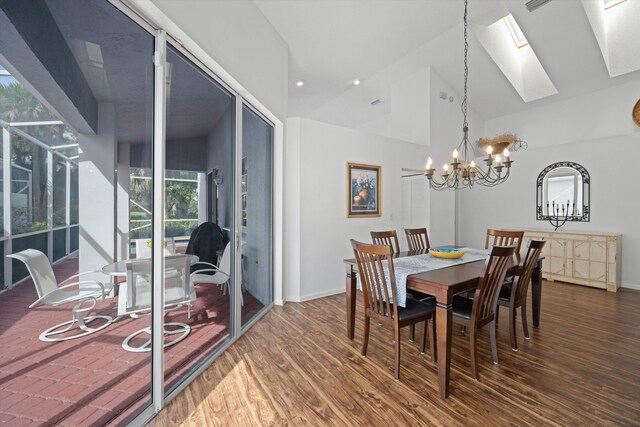 dining area featuring a skylight, a notable chandelier, baseboards, and wood finished floors