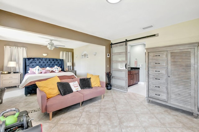 bedroom with visible vents, a ceiling fan, a barn door, connected bathroom, and light tile patterned floors