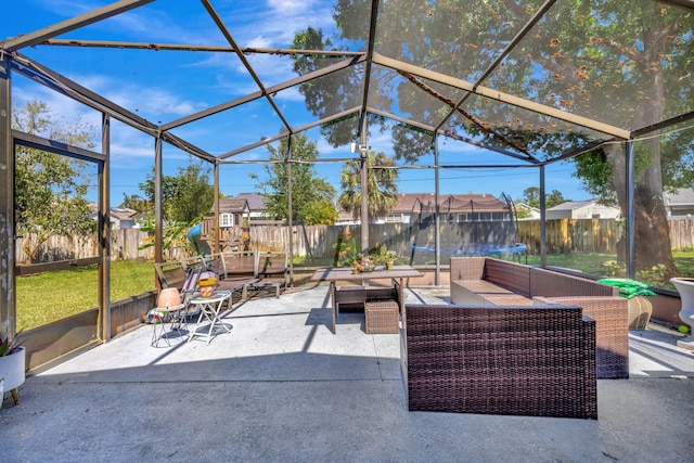 view of patio / terrace featuring glass enclosure, a trampoline, a fenced backyard, and outdoor lounge area