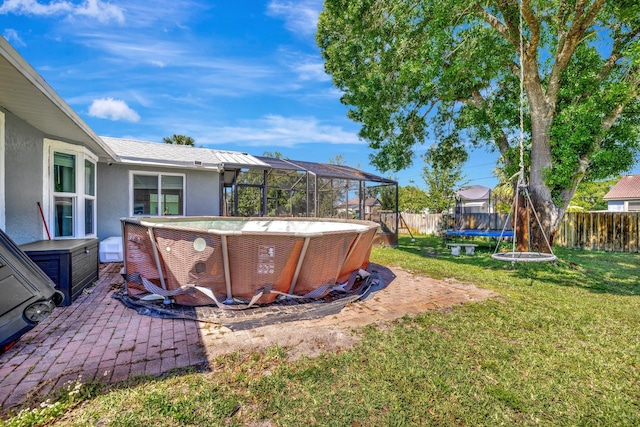 view of yard featuring glass enclosure, a patio, a fenced in pool, a fenced backyard, and a trampoline