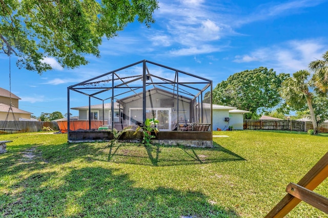rear view of property featuring glass enclosure, a lawn, and a fenced backyard