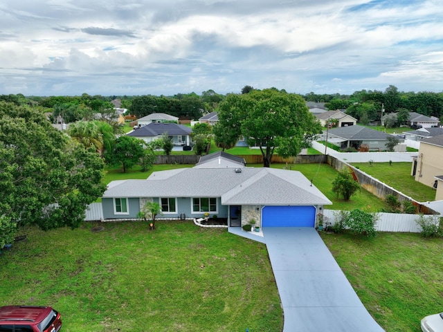 view of front of home featuring driveway, fence, a residential view, a front yard, and an attached garage