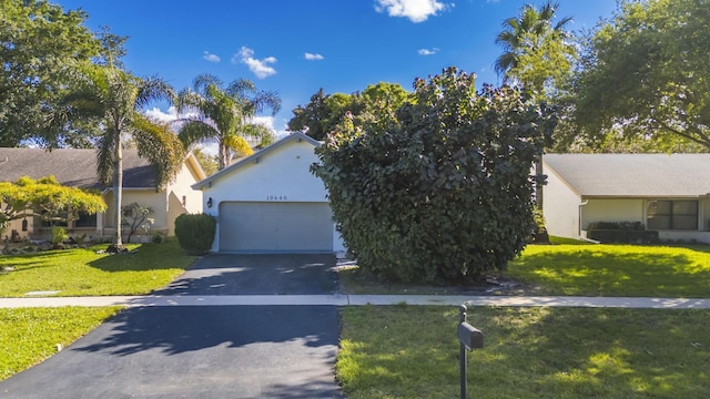 obstructed view of property with driveway, stucco siding, a garage, and a front yard