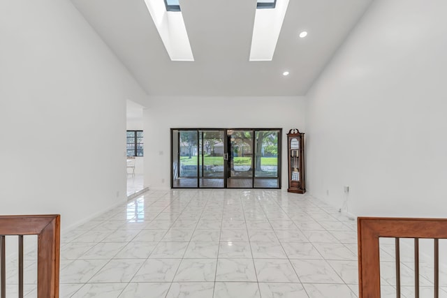 spare room with a skylight, marble finish floor, french doors, high vaulted ceiling, and recessed lighting