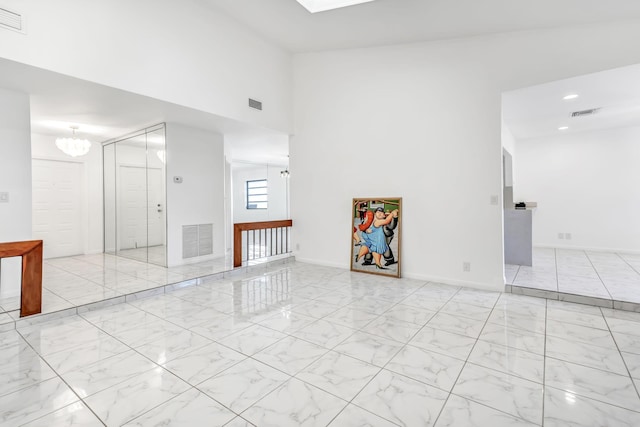 spare room with marble finish floor, visible vents, and an inviting chandelier