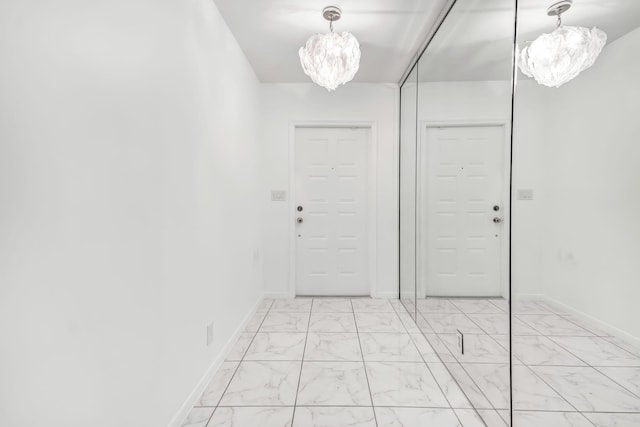 interior space featuring marble finish floor, baseboards, and an inviting chandelier