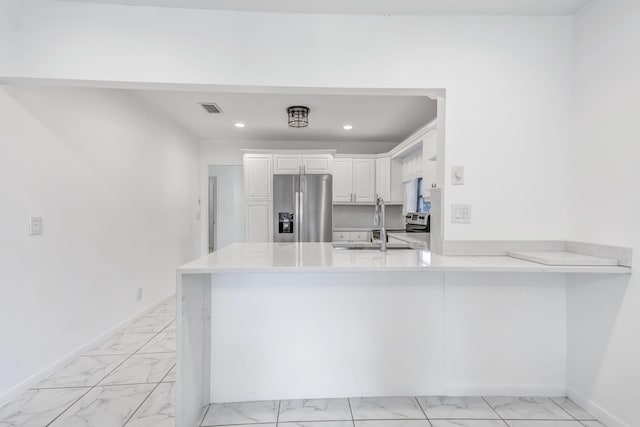 kitchen featuring a peninsula, marble finish floor, stainless steel fridge, and visible vents