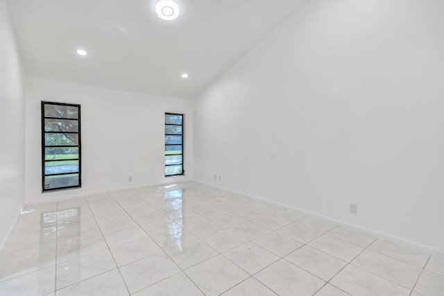 empty room featuring vaulted ceiling, recessed lighting, baseboards, and a healthy amount of sunlight