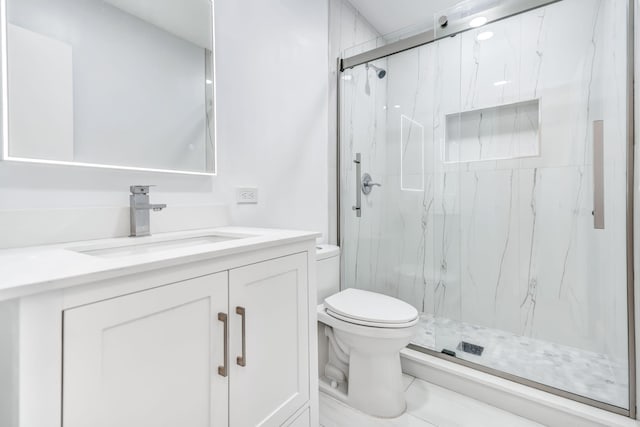 bathroom with a marble finish shower, vanity, and toilet