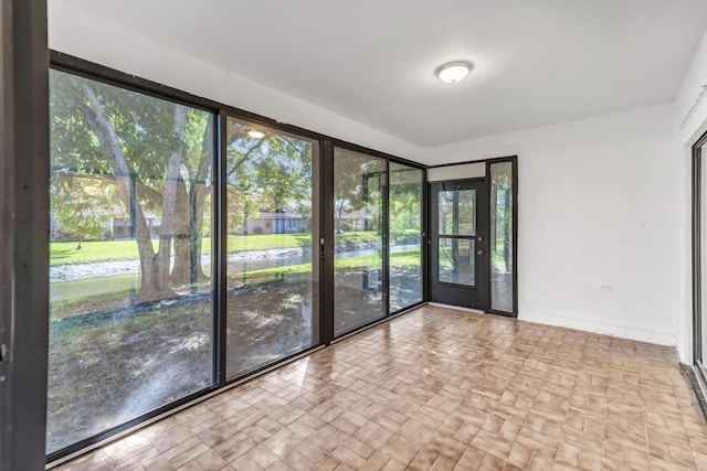 spare room with brick floor, baseboards, and a sunroom