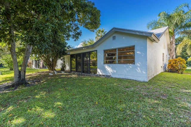 rear view of property with a lawn and stucco siding