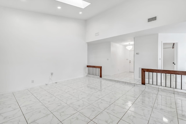 spare room featuring recessed lighting, a high ceiling, a skylight, visible vents, and marble finish floor