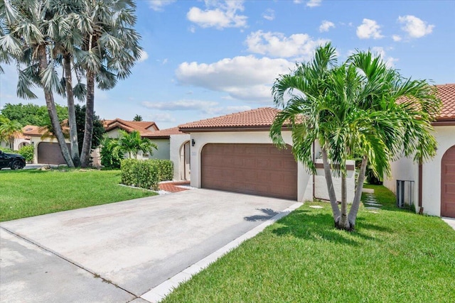 mediterranean / spanish-style home with stucco siding, driveway, an attached garage, a front yard, and a tiled roof