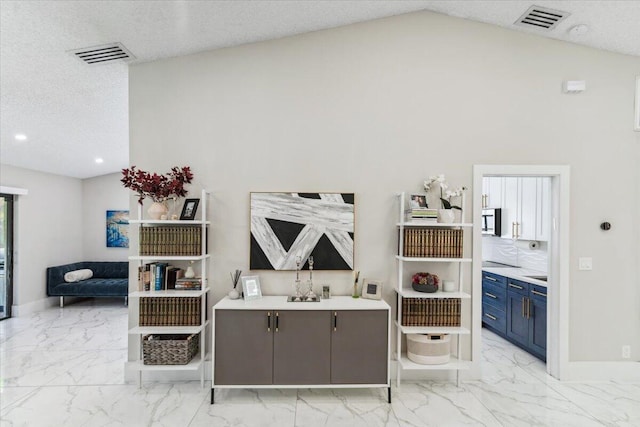 living room featuring lofted ceiling, visible vents, marble finish floor, and a textured ceiling