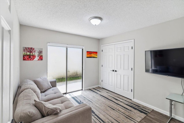 living room featuring wood finished floors, baseboards, and a textured ceiling