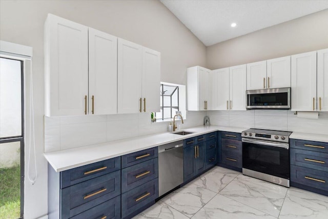 kitchen with blue cabinetry, backsplash, appliances with stainless steel finishes, and a sink