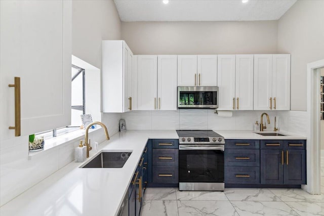 kitchen with a sink, stainless steel appliances, light countertops, and white cabinetry