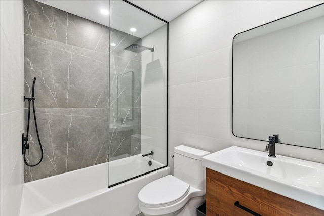 full bathroom with vanity, toilet, tile walls, and washtub / shower combination