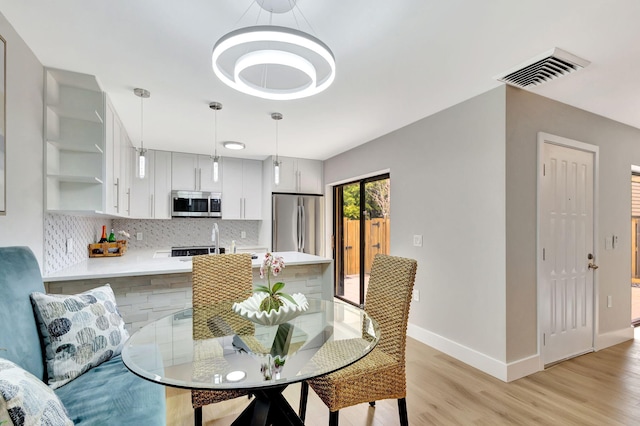 dining room featuring light wood-style flooring, visible vents, and baseboards