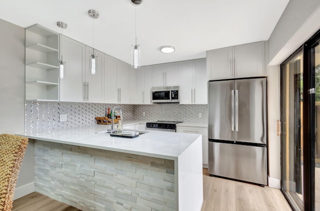 kitchen with open shelves, stainless steel appliances, tasteful backsplash, light countertops, and a peninsula