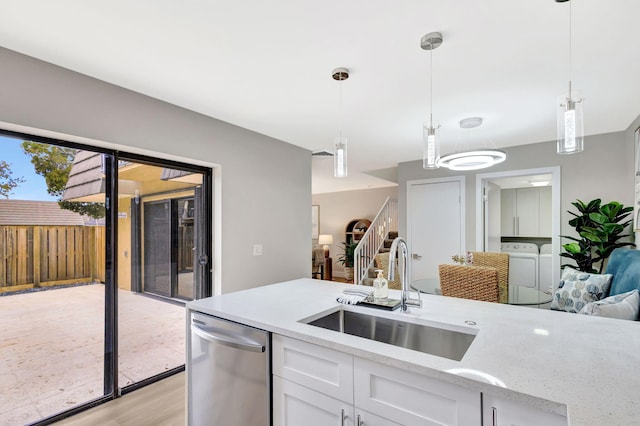 kitchen with a sink, white cabinets, dishwasher, washer and clothes dryer, and pendant lighting