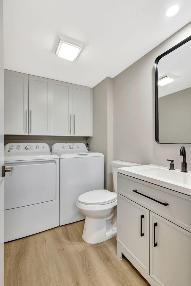 bathroom with washing machine and dryer, vanity, toilet, and wood finished floors