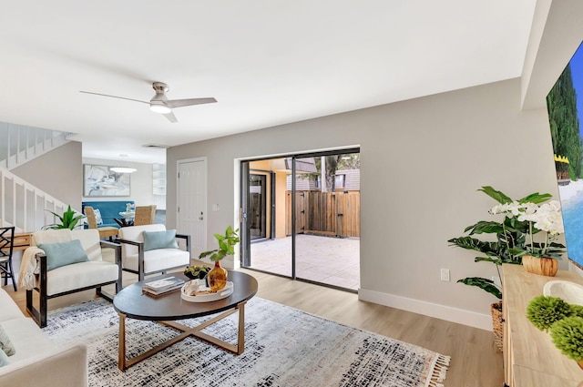 living area with visible vents, baseboards, ceiling fan, stairway, and wood finished floors