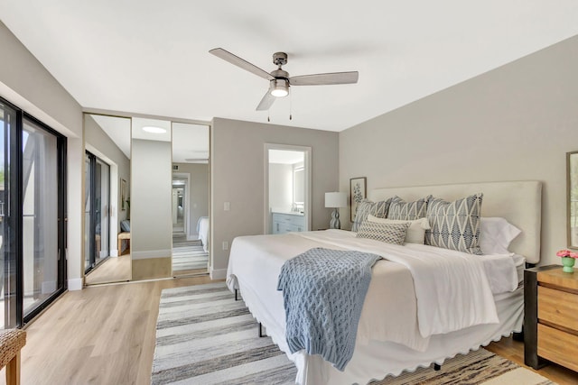 bedroom featuring light wood-style floors, ensuite bath, baseboards, and ceiling fan