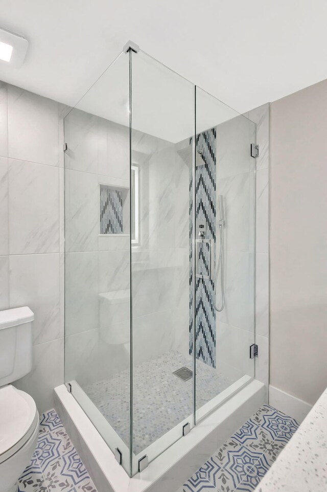 full bath featuring a stall shower, baseboards, toilet, and tile patterned floors