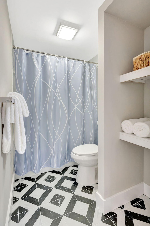 bathroom featuring curtained shower, toilet, and baseboards