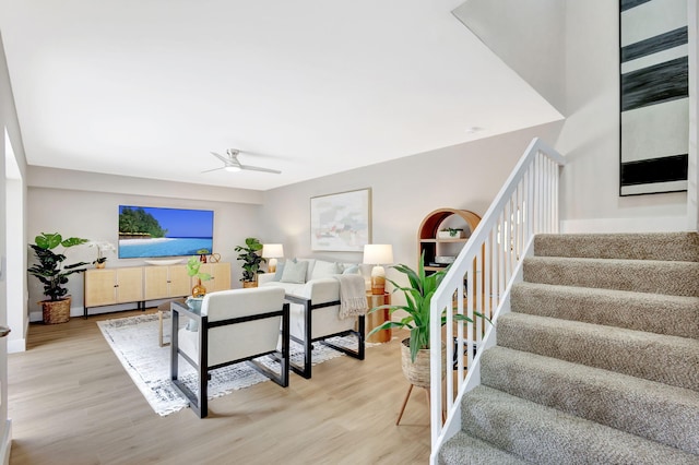 living room with stairs, ceiling fan, and wood finished floors