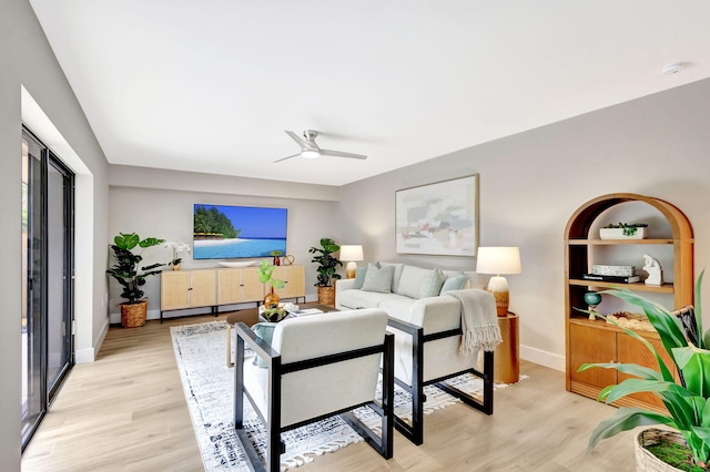 living room featuring light wood-type flooring, ceiling fan, and baseboards