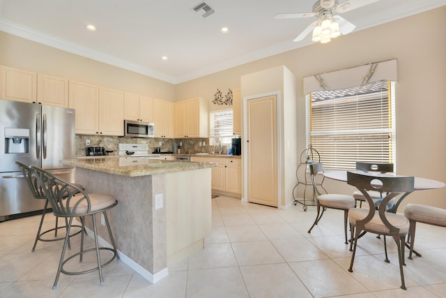 kitchen featuring visible vents, a kitchen island, stainless steel appliances, crown molding, and backsplash