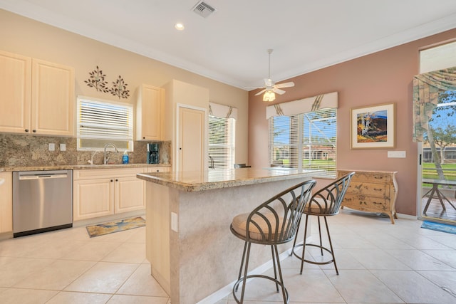 kitchen with light tile patterned floors, a breakfast bar area, a sink, stainless steel dishwasher, and ornamental molding