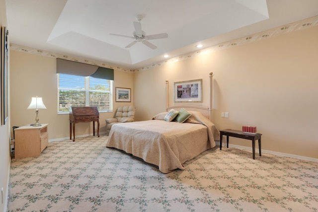 bedroom featuring a ceiling fan, baseboards, a tray ceiling, and carpet flooring