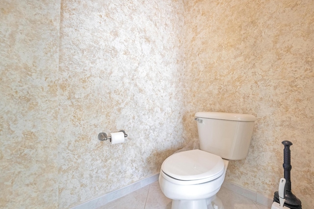 bathroom with tile patterned flooring, baseboards, and toilet