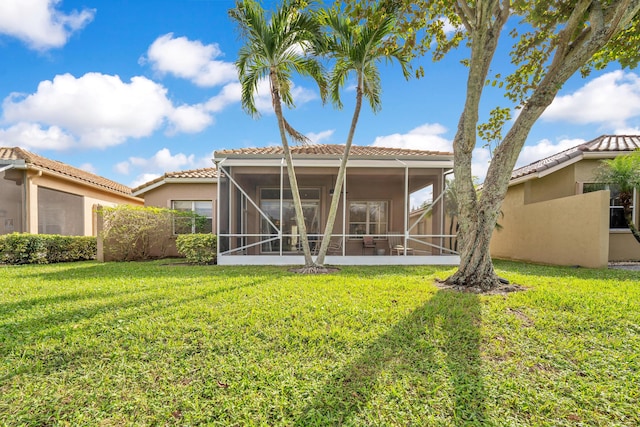 back of property featuring a sunroom, a tile roof, a yard, and stucco siding