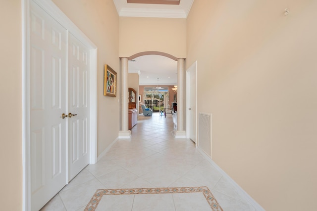 corridor featuring light tile patterned floors, decorative columns, visible vents, and crown molding