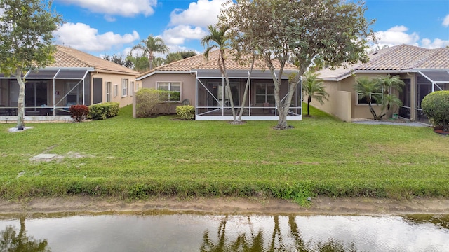 rear view of house featuring a tile roof, a yard, stucco siding, a water view, and glass enclosure