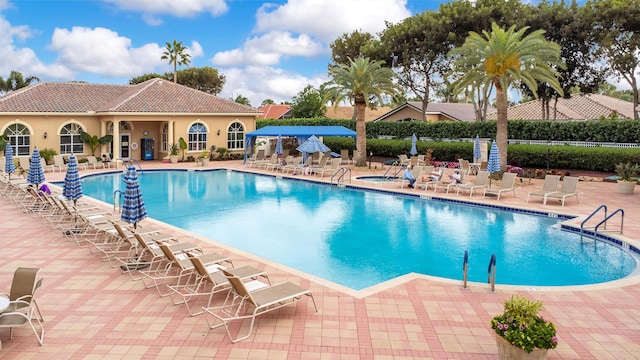 community pool with a patio area and fence