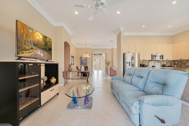 living room with light tile patterned floors, recessed lighting, arched walkways, ornamental molding, and ceiling fan with notable chandelier